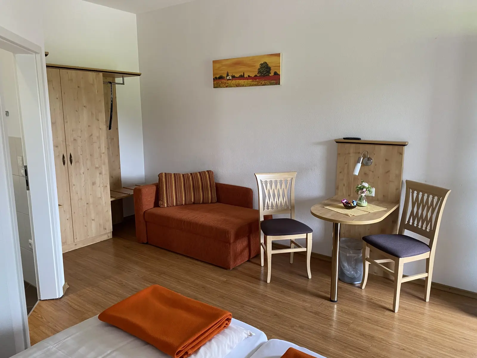 Einzelzimmer mit Bett, Tisch und Sitzbereich